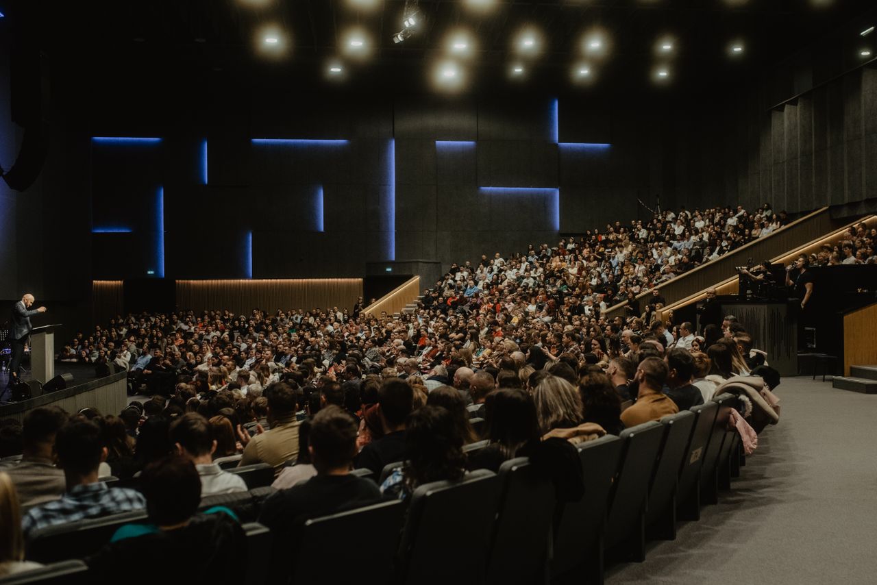 Crafting Captivating Headlines: Your awesome post title goes here A large audience attentively listens to a speaker at a conference in Oradea, Romania.