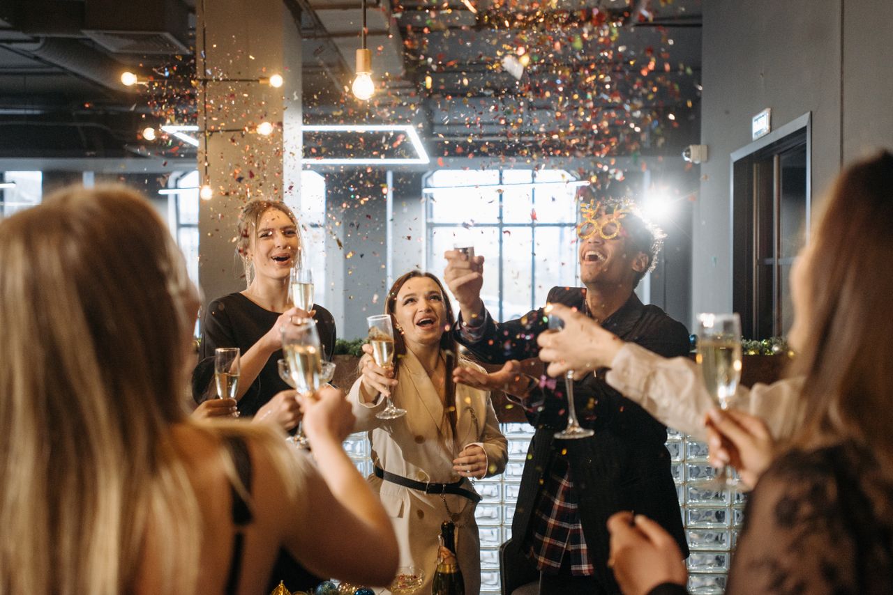Mastering the First Impression: Your intriguing post title goes here A group of friends celebrates indoors with champagne and confetti in a festive atmosphere.
